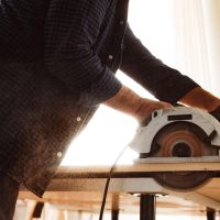 carpenter-hands-cutting-wood-with-electrical-saw carpenter-hands-cutting-wood-with-electrical-saw